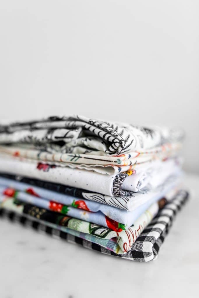 A stack of fabric with various patterns and colours close up