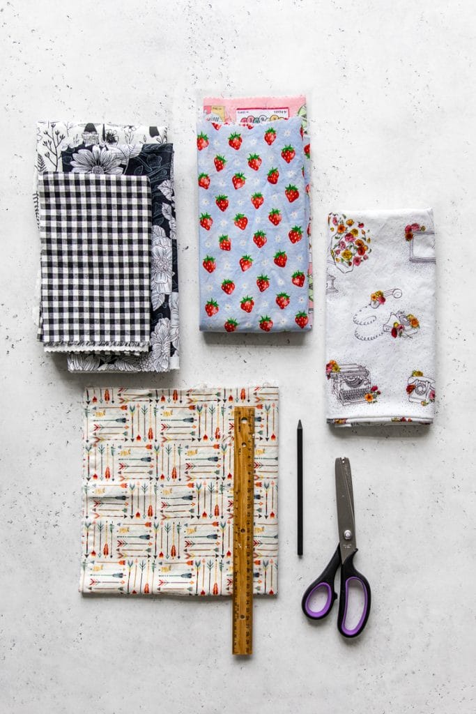 Various pieces of fabric laid out on a table with scissors, pencil and ruler