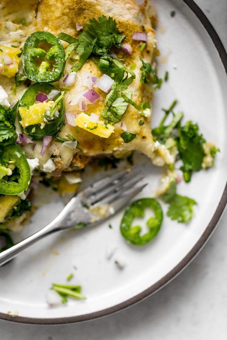 Close up of Pork Enchiladas Al Pastor served on a plate with jalapeños and pineapple