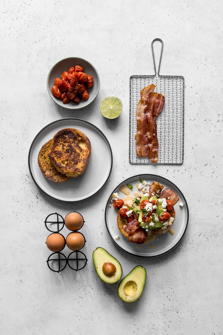 Plates with French Toast, loaded French Toast, eggs, avocados, tomatoes, and bacon