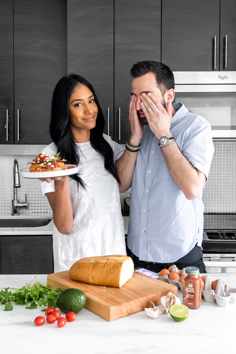 Interracial couple holding plate of French Toast behind a counter with various ingredients