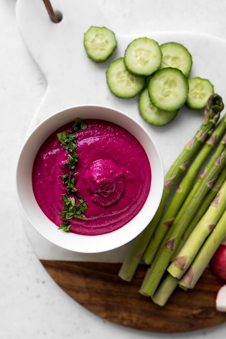 White Bean and Beet Hummus in a white bowl with parsley