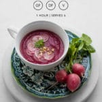 Roasted Beet Soup with Fennel and Orange in a white bowl styled on a colourful plate and marble board