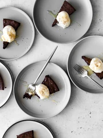 Six plates of flourless chocolate cake with whipped cream and sesame seeds
