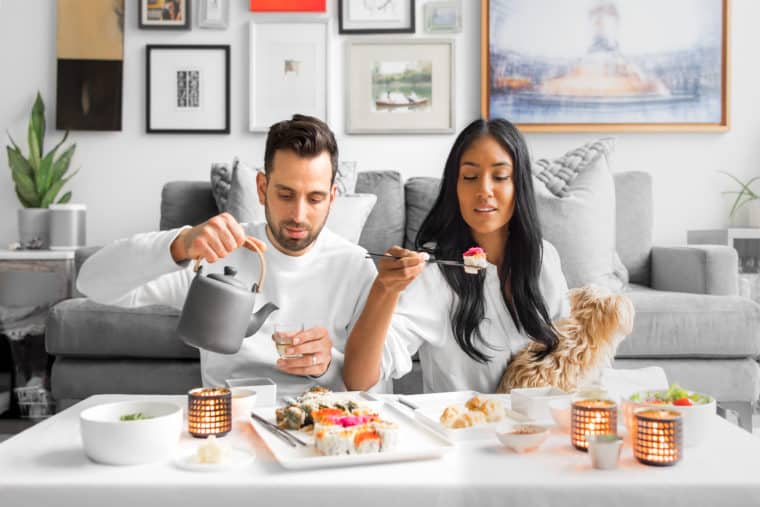 Interracial couple enjoying sushi sitting in front of their couch