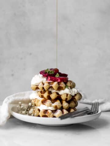 Belgian-Waffles with Whipped Cream and Blood Oranges getting Maple Syrup Drizzled on Top
