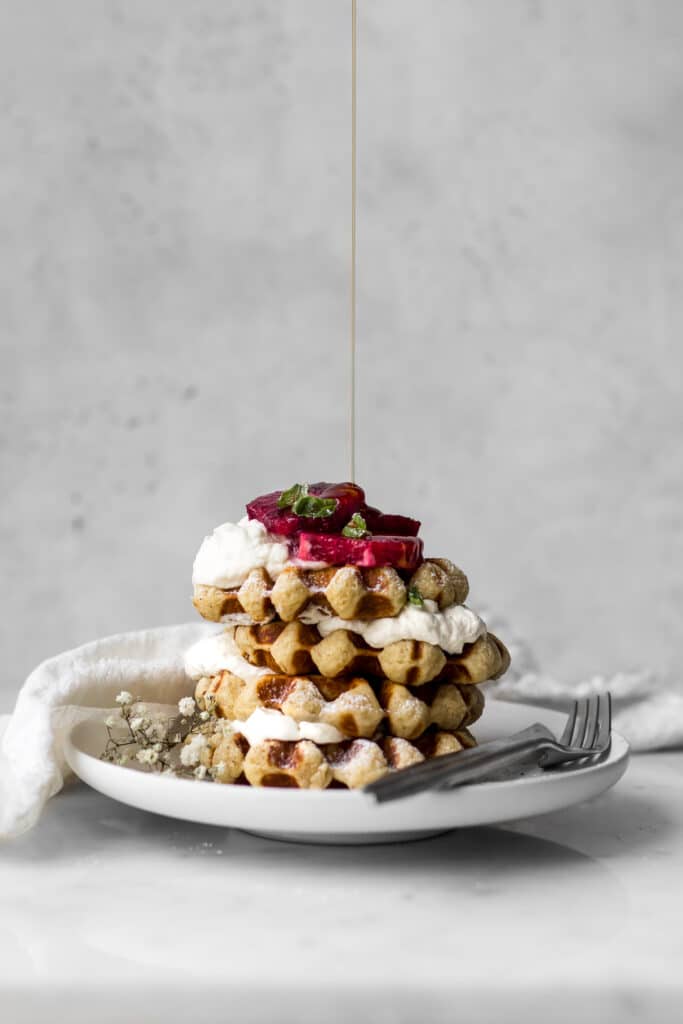 Belgian-Waffles with Whipped Cream and Blood Oranges getting Maple Syrup Drizzled on Top