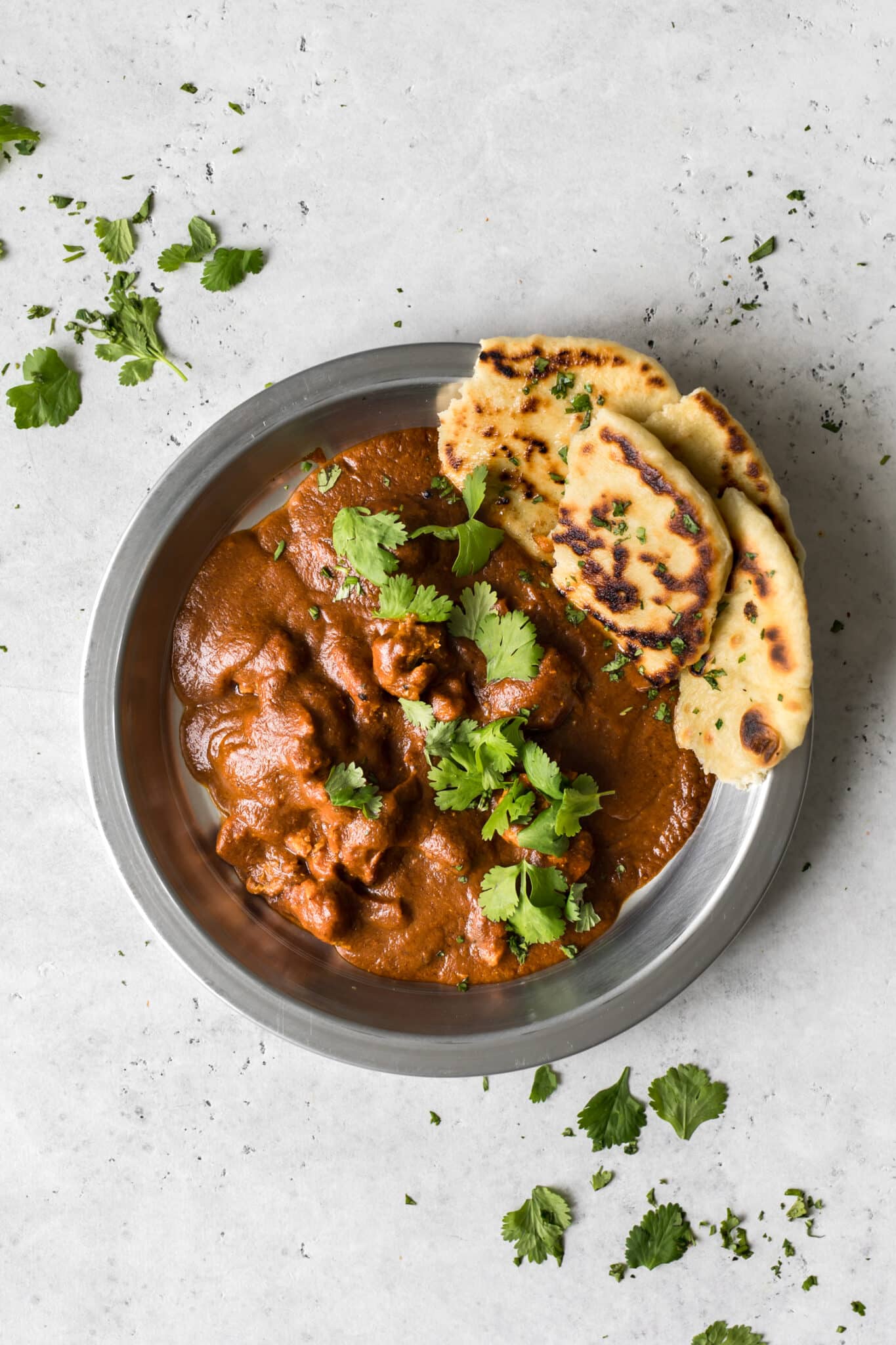 Butter Chicken with Coconut Milk in Silver Bowl with Cilantro and Naan