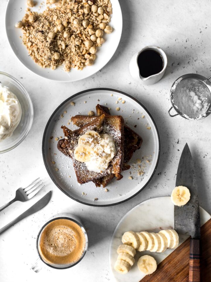 Cinnamon French Toast with whipped cream with sliced bananas, hazelnuts, coffee and maple syrup