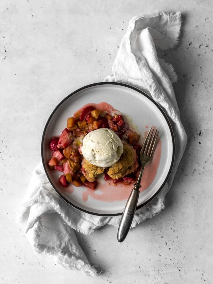 Single plate serving of strawberry rhubarb crisp with ice cream