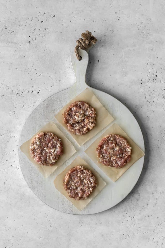 4 sausage patties on parchment paper and white wooden board