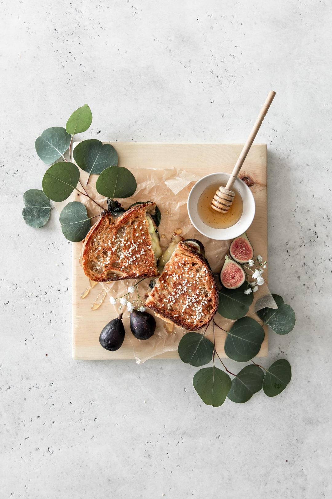 Gourmet grilled cheese halves on a wooden board with figs and honey.