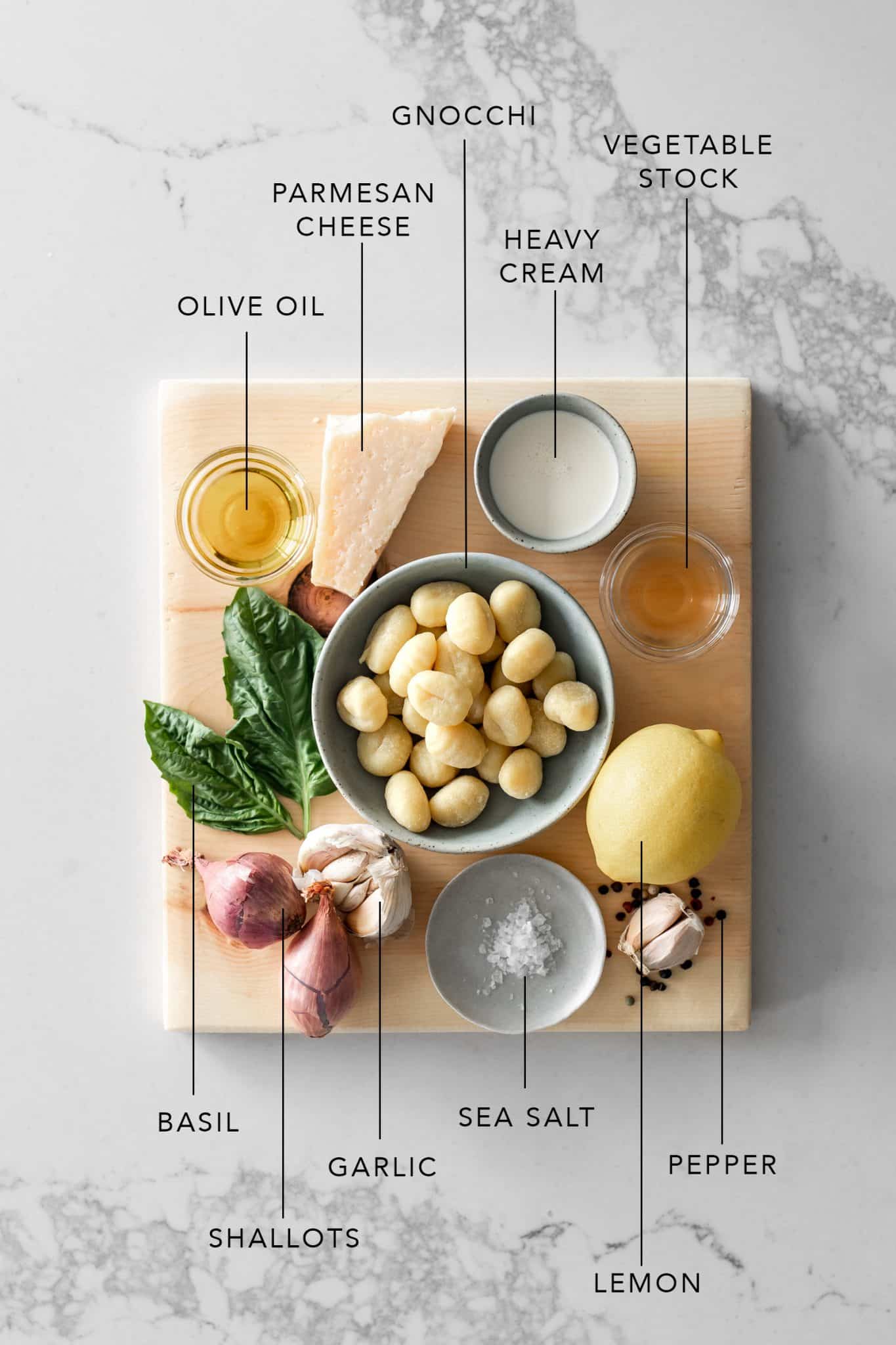 Wood board with olive oil, parmesan, gnocchi, cream, vegetable stock, basil, shallots, garlic, sea salt, lemon and peppercorns