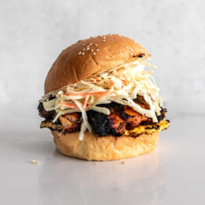 BBQ Jerk Chicken Sandwich on a sesame seed bun with grilled pineapple and coleslaw