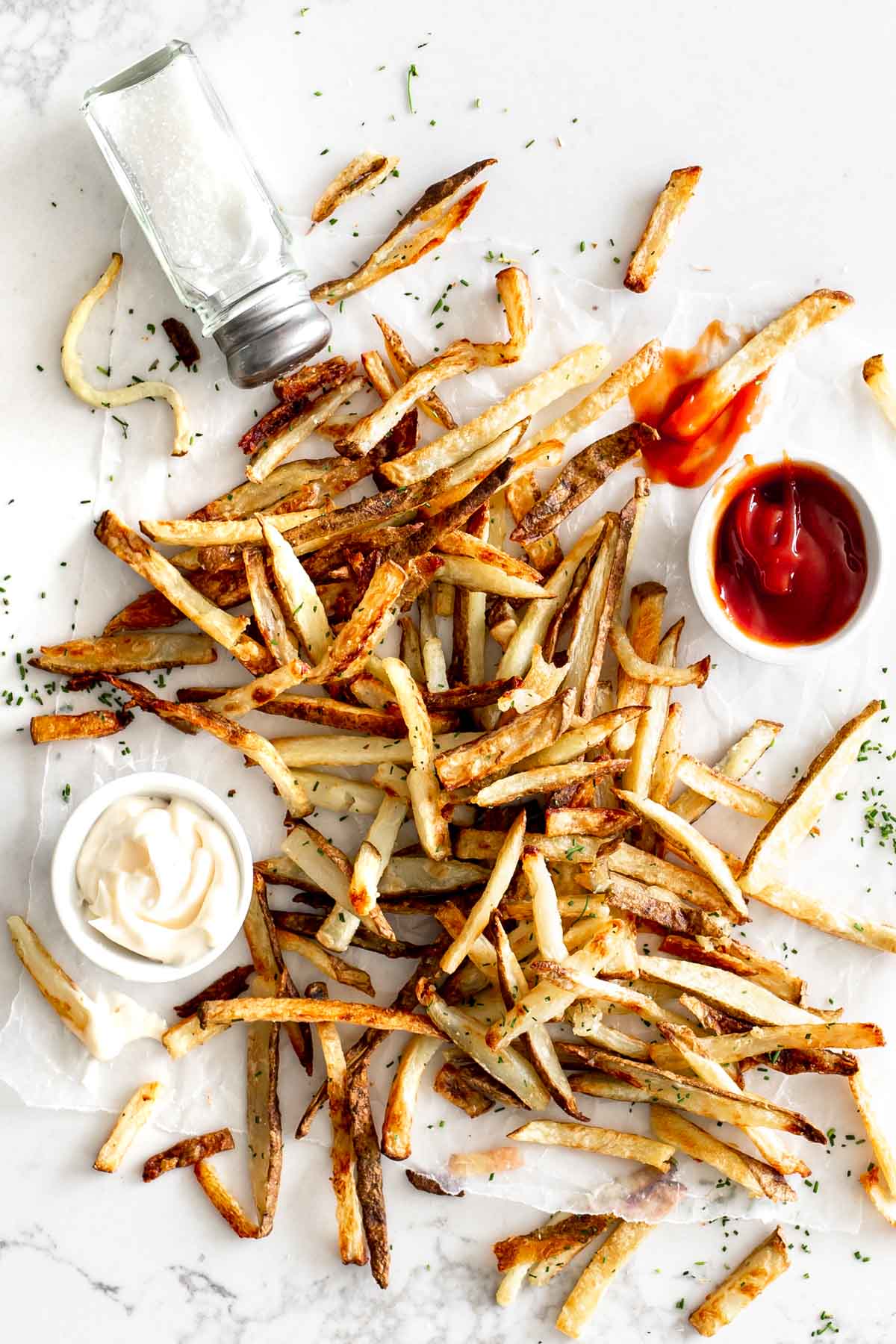 Crispy Oven Baked French Fries on marble with ketchup, mayo and salt