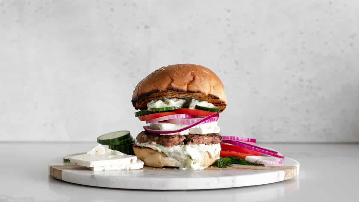 Turkey Burger on a bun with tzatziki sauce, feta cheese, red onion, tomato and cucumbers