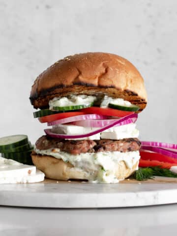 Greek Turkey Burger with Tzatziki, Feta Cheese, Red Onion, and Cucumbers on a marble board