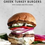 Turkey Burger on a bun with feta cheese, tzatziki sauce, red onion, tomato and cucumbers
