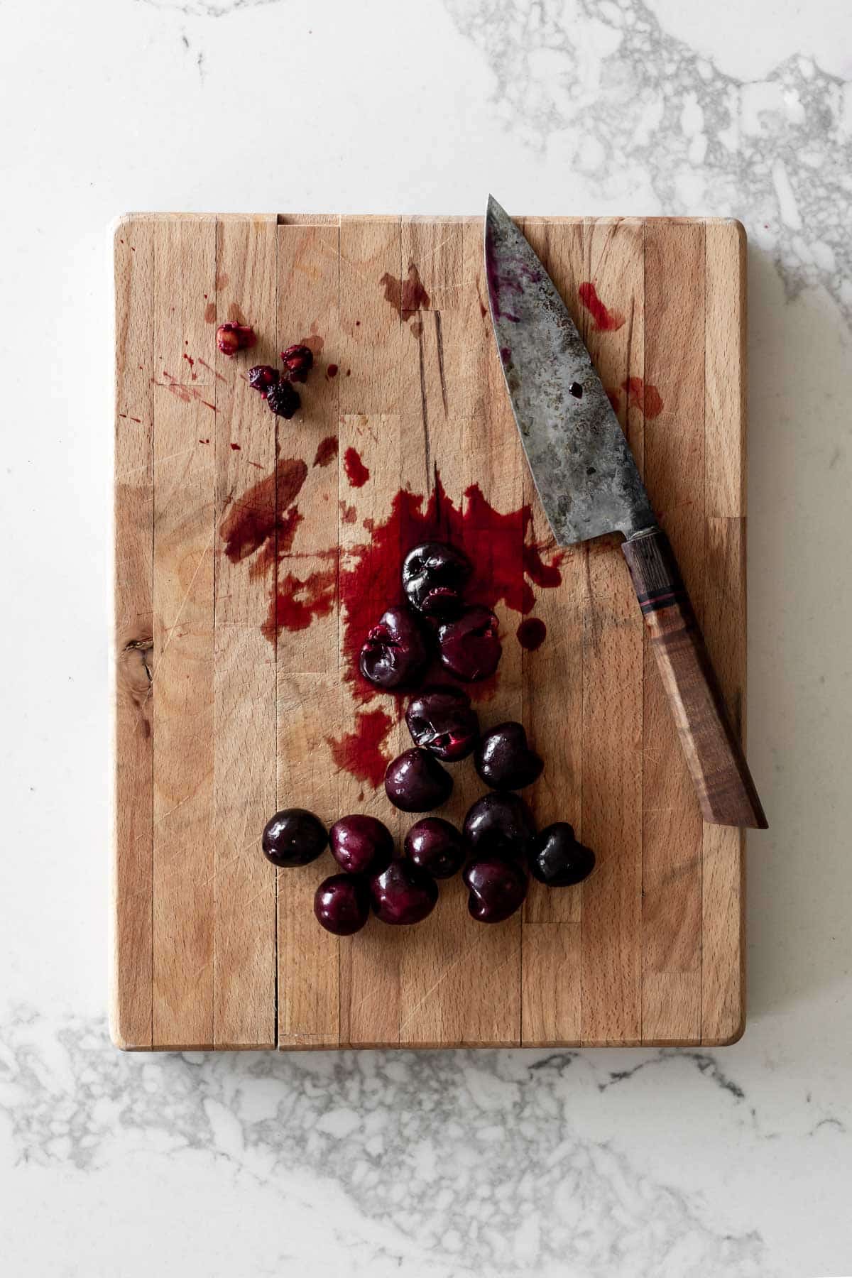 Crushed cherries on a cutting board with a knife
