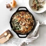 Green Bean Casserole in a Lodge Skillet with garlic, onion, parmesan and napkin around it