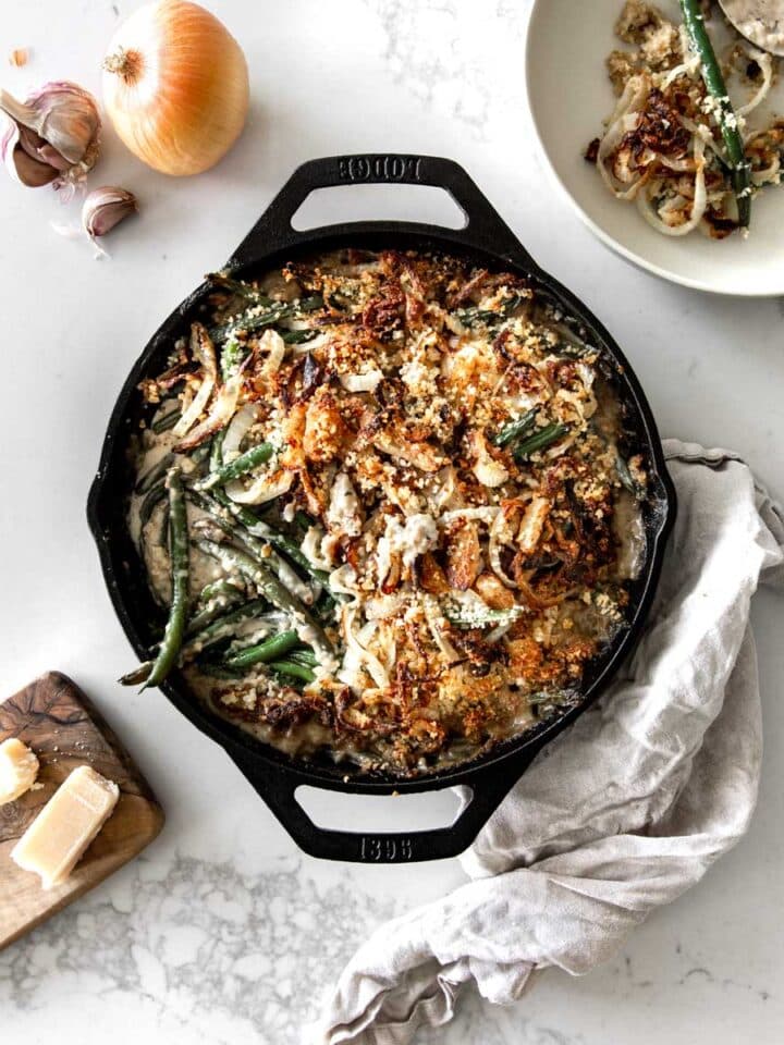 Green Bean Casserole in a Lodge Skillet with garlic, onion, parmesan and napkin around it
