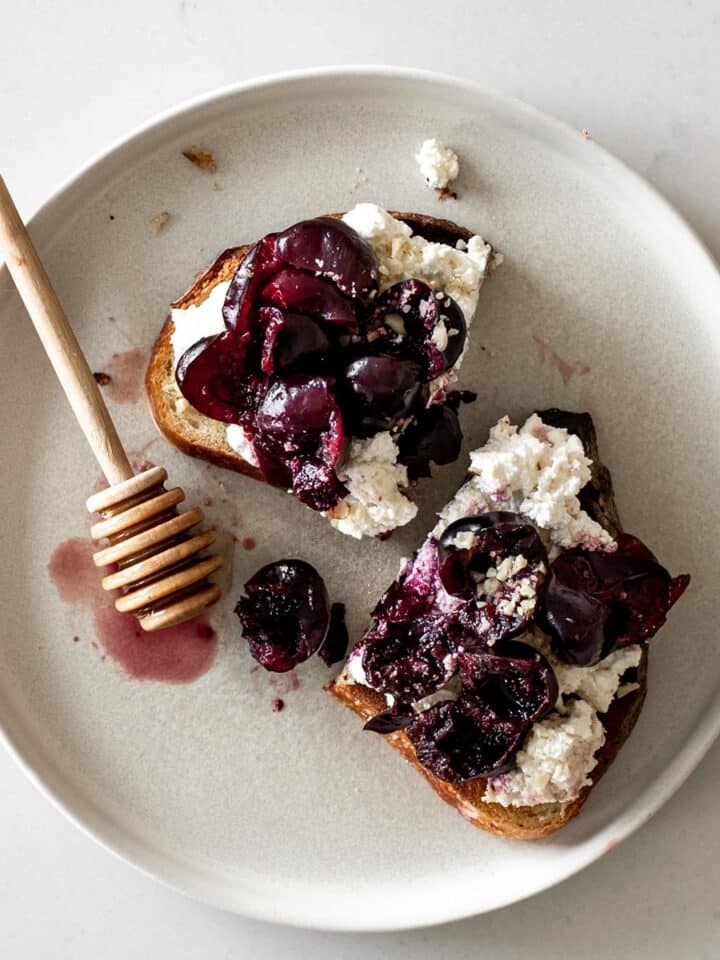 Cherry Ricotta Toast on a plate with honey stick