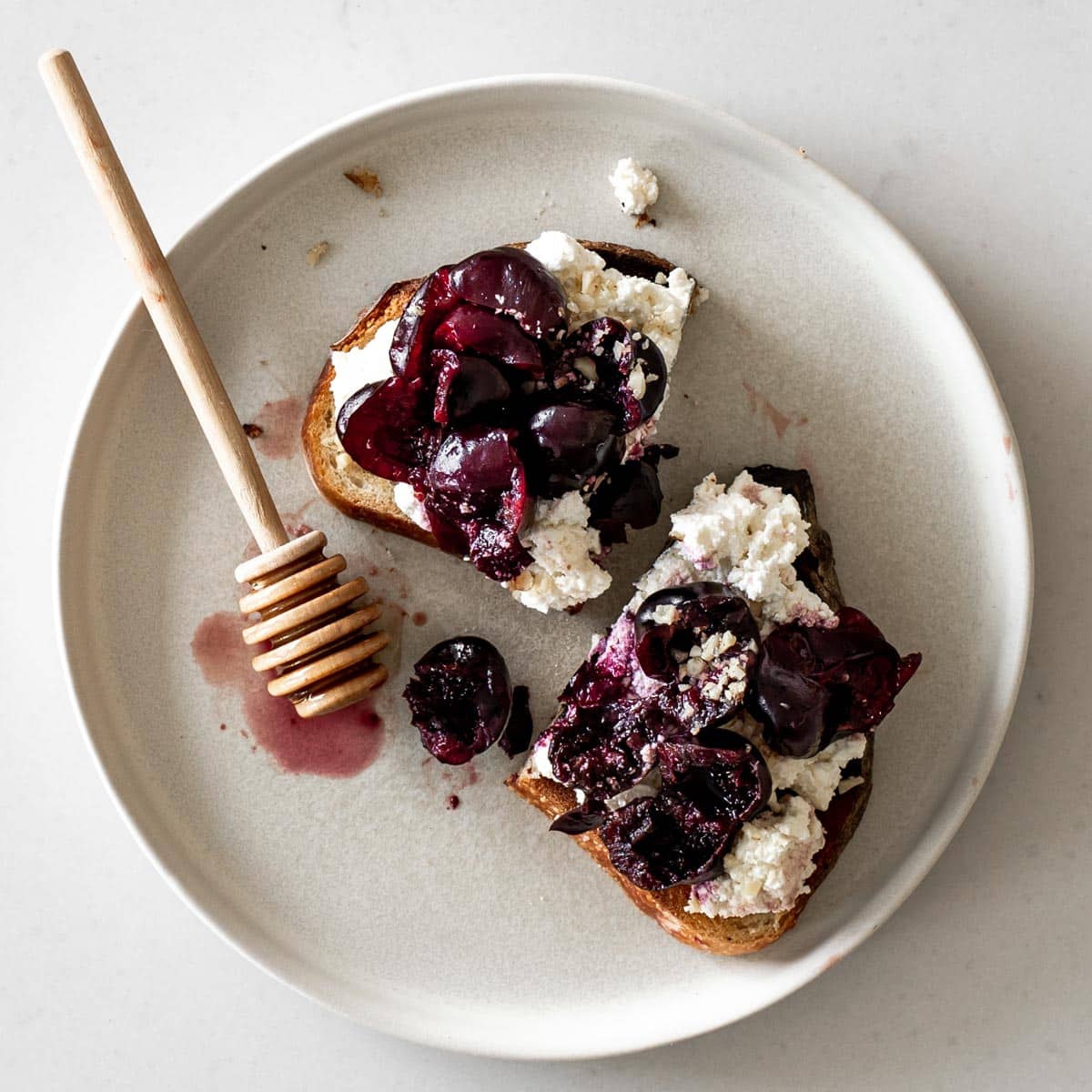 Cherry Ricotta Toast on a plate with honey stick