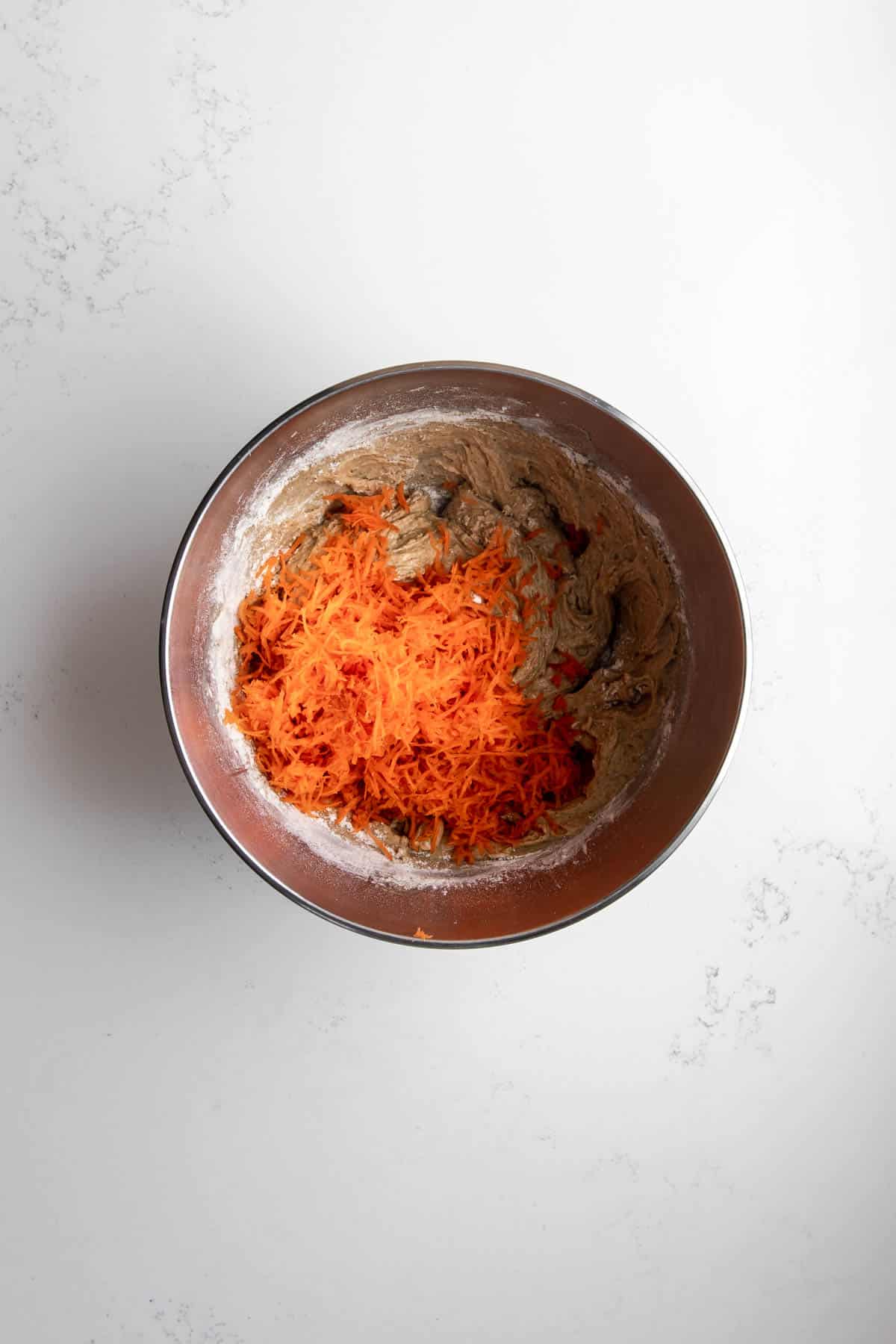 Carrot Cake Muffin Batter with grated carrots on top.