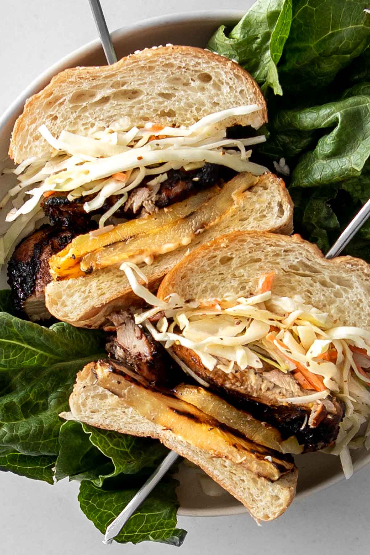 Grilled Jerk Chicken Sandwich halves pierced with skewers and laying on a bed of lettuce.