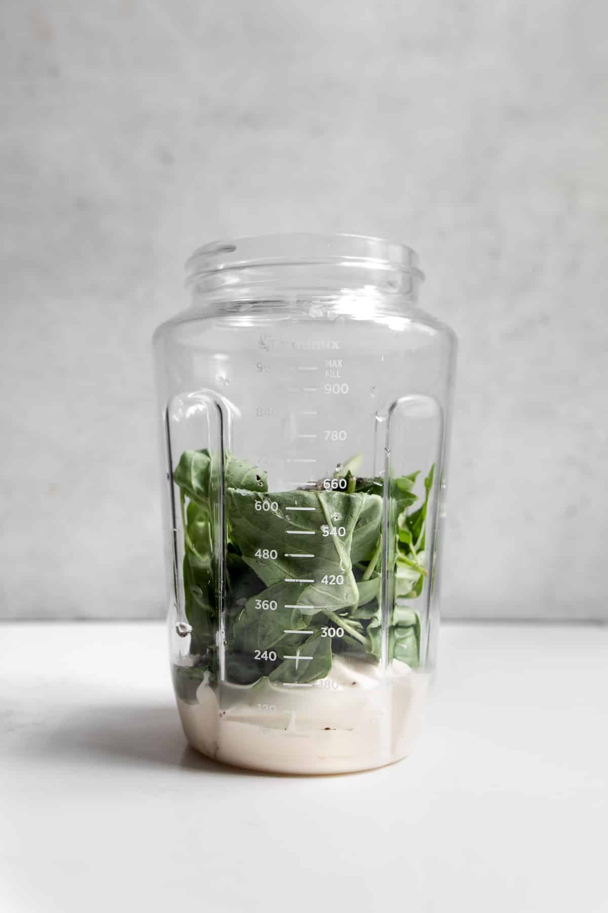 Mayonnaise and basil in a immersion blender container.