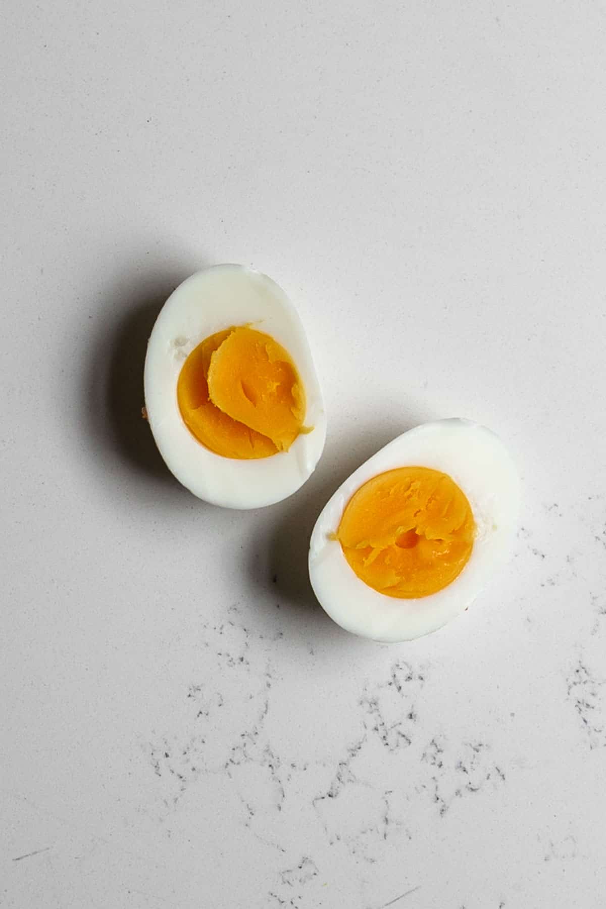 A hard boiled egg cut in half on a marble table.