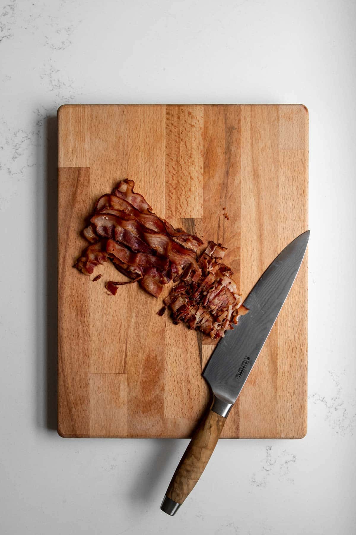 Cooked bacon on a cutting board with a knife.