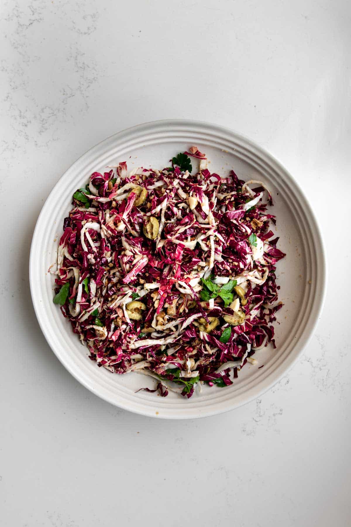 Radicchio Salad in a bowl topped with olives, parsley and walnuts.