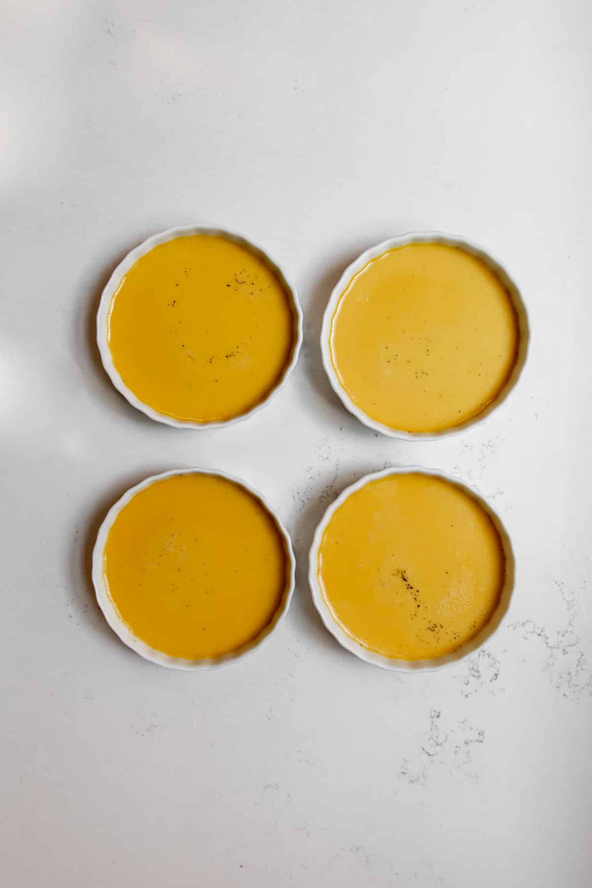 Pumpkin creme brûlées on a countertop before adding sugar topping.