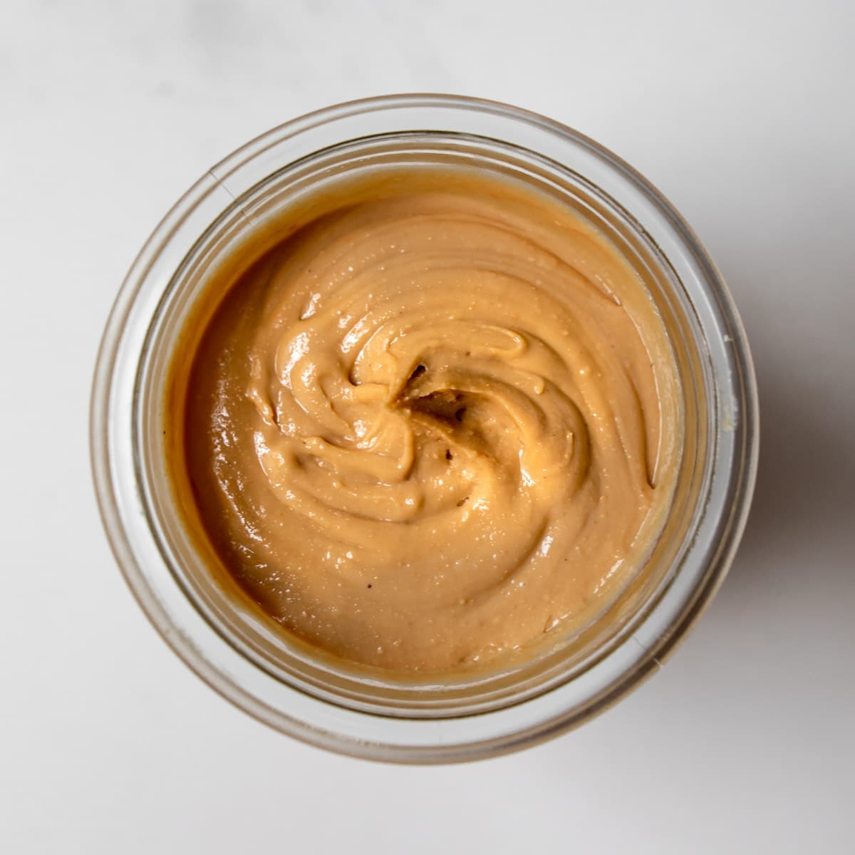 Overhead close-up view of homemade cashew butter in a glass jar.