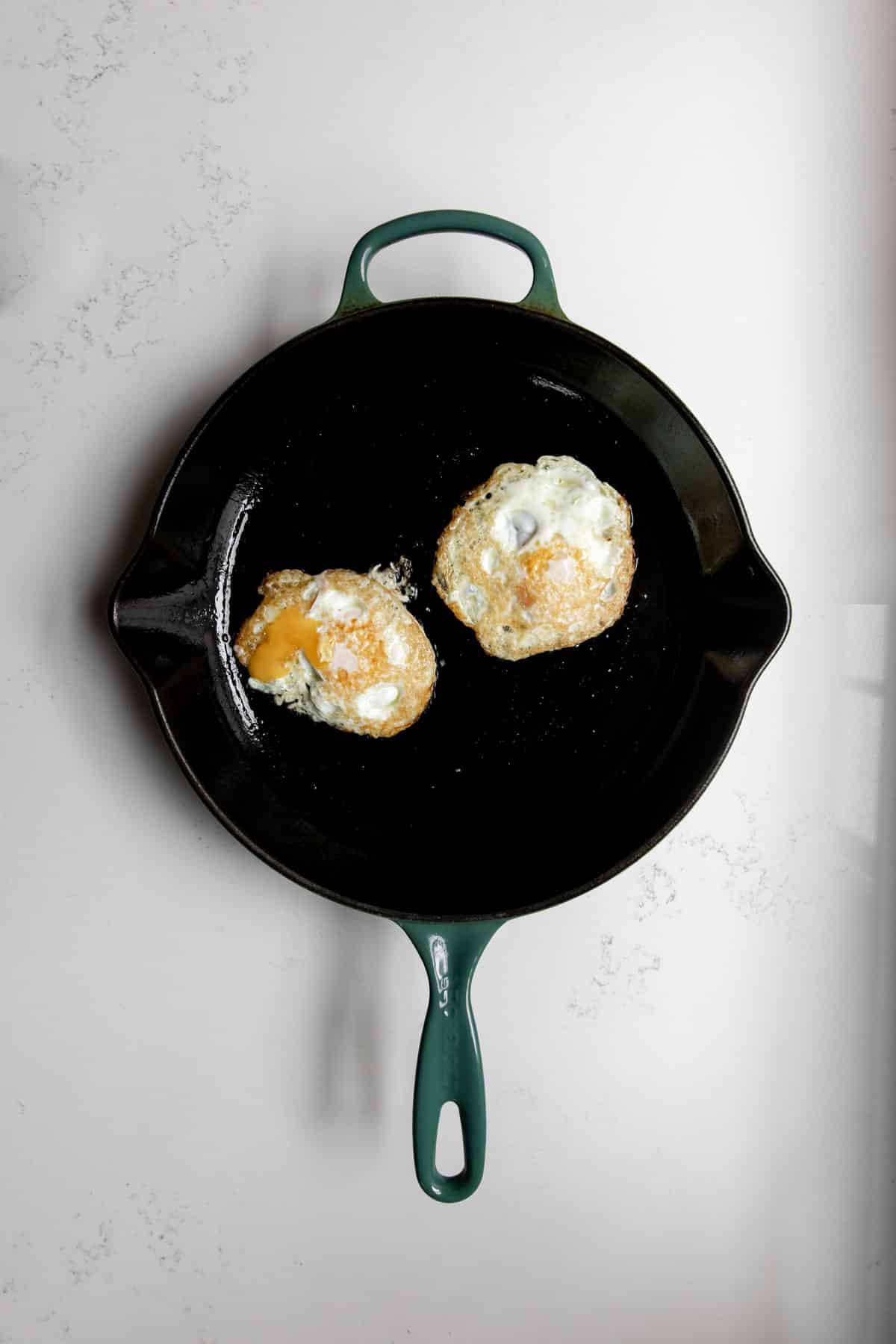 Two over-easy eggs on a cast iron skillet.
