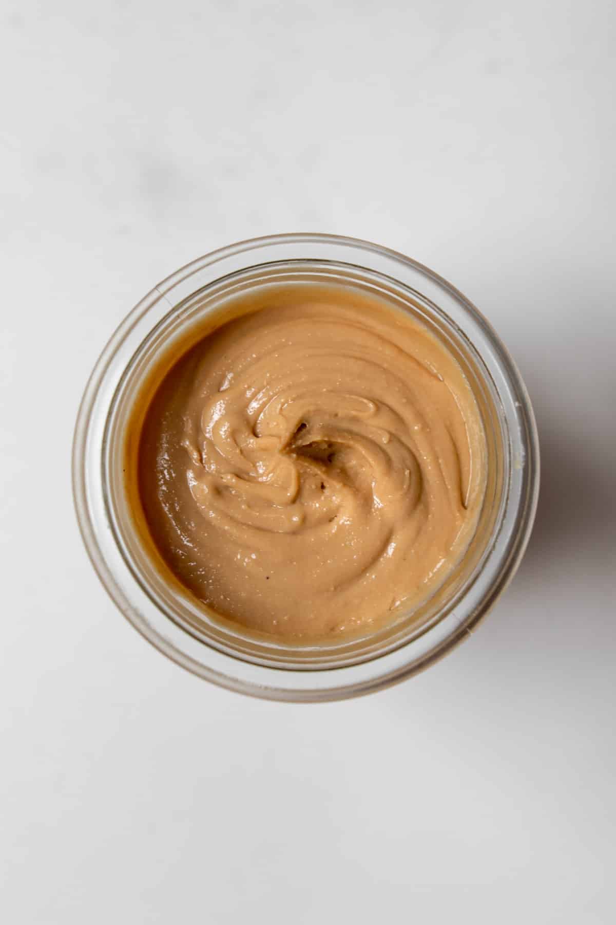Overhead close-up of cashew butter in a glass jar.