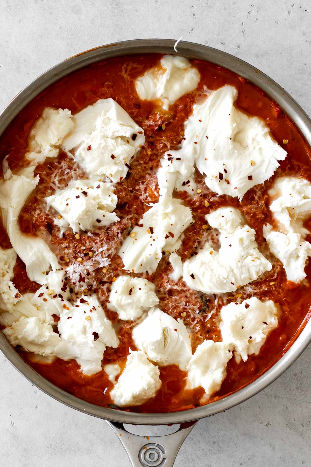 mozzarella shredded and laid overtop vodka sauce with red pepper flakes.