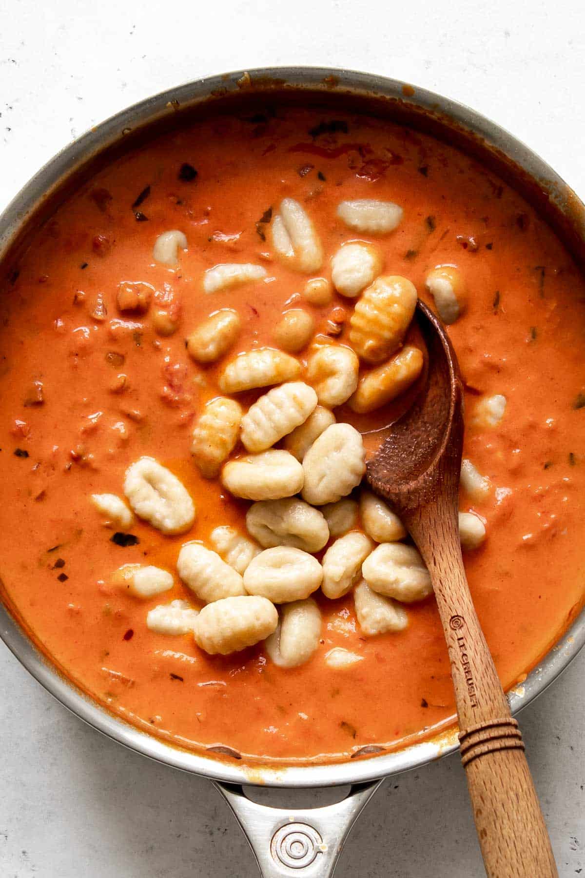 gnocchi added to a pan with creamy vodka sauce with spoon.