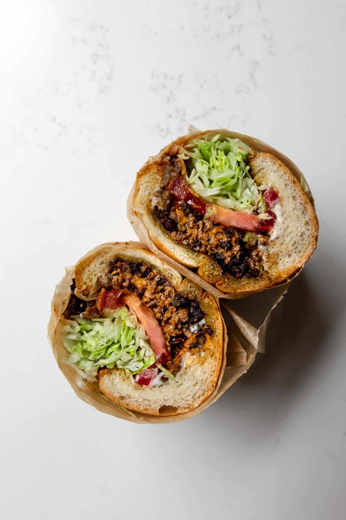 Chopped cheese sandwich wrapped in parchment paper cut in half.