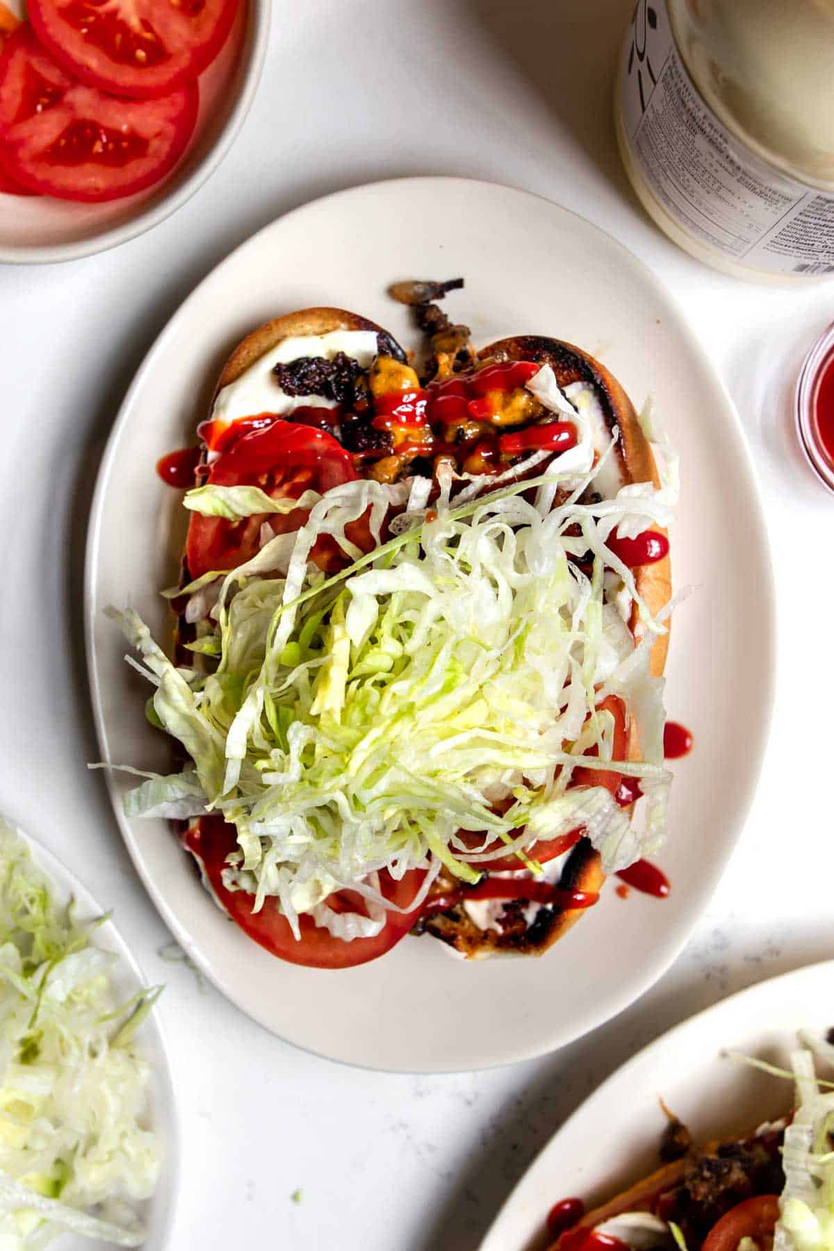 Chopped cheese sandwich on a plate topped with lettuce and tomato.