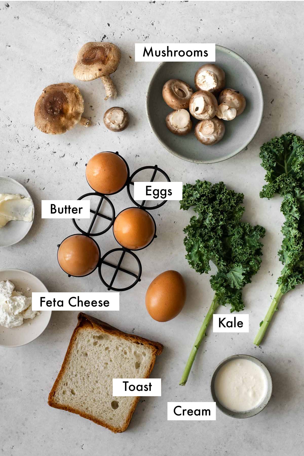 ingredients for coddled eggs with mushroom and kale on a table labelled with text graphics.