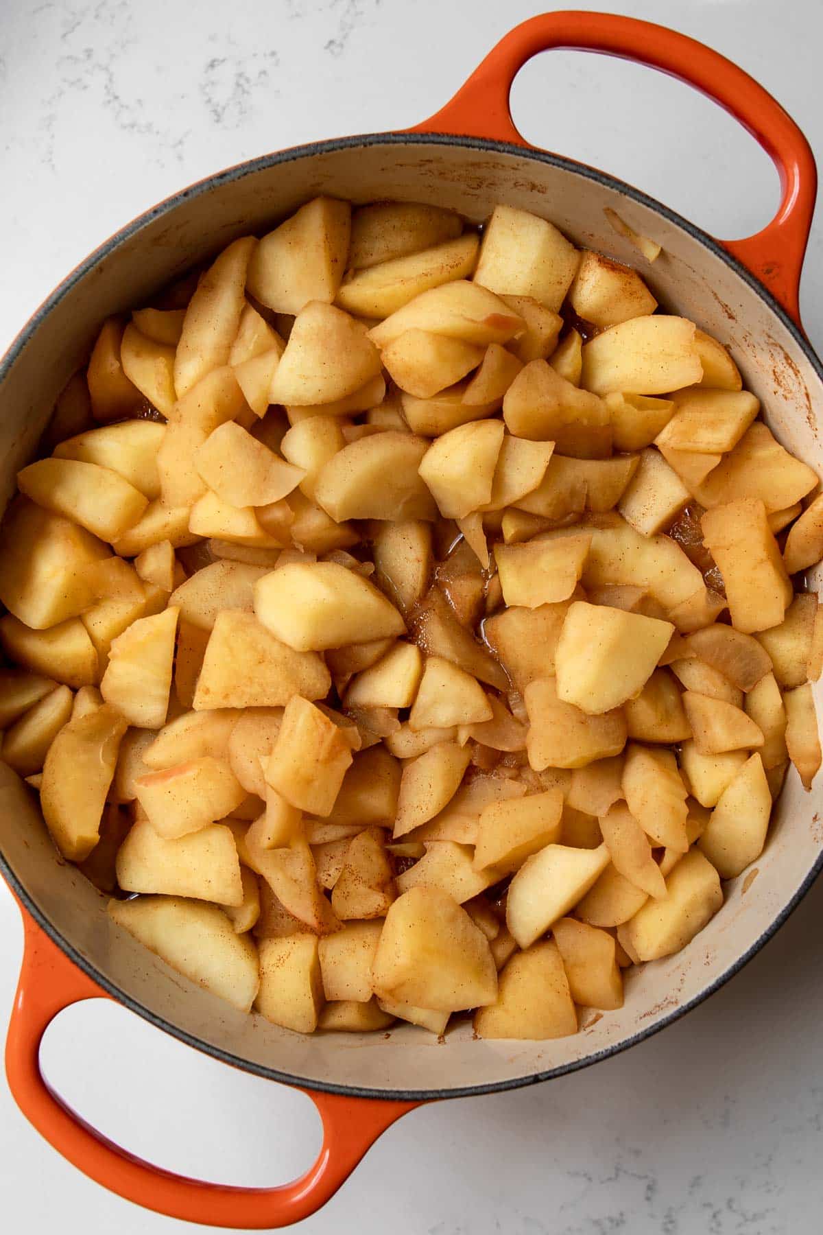 cut and cored apples tossed in cinnamon in a Dutch oven pot softened from cooking