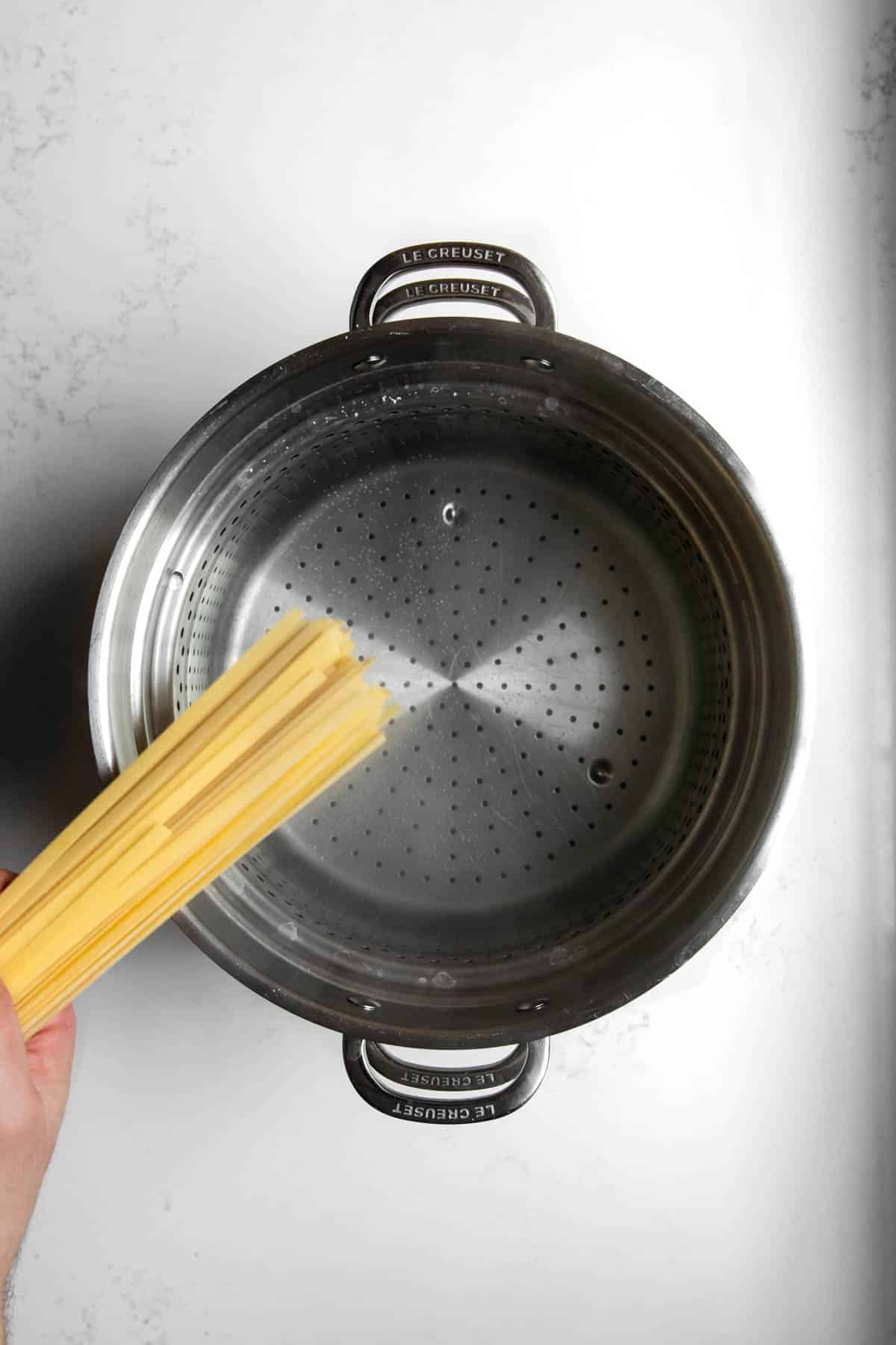 fettuccine noodles going into a pot of boiling water.