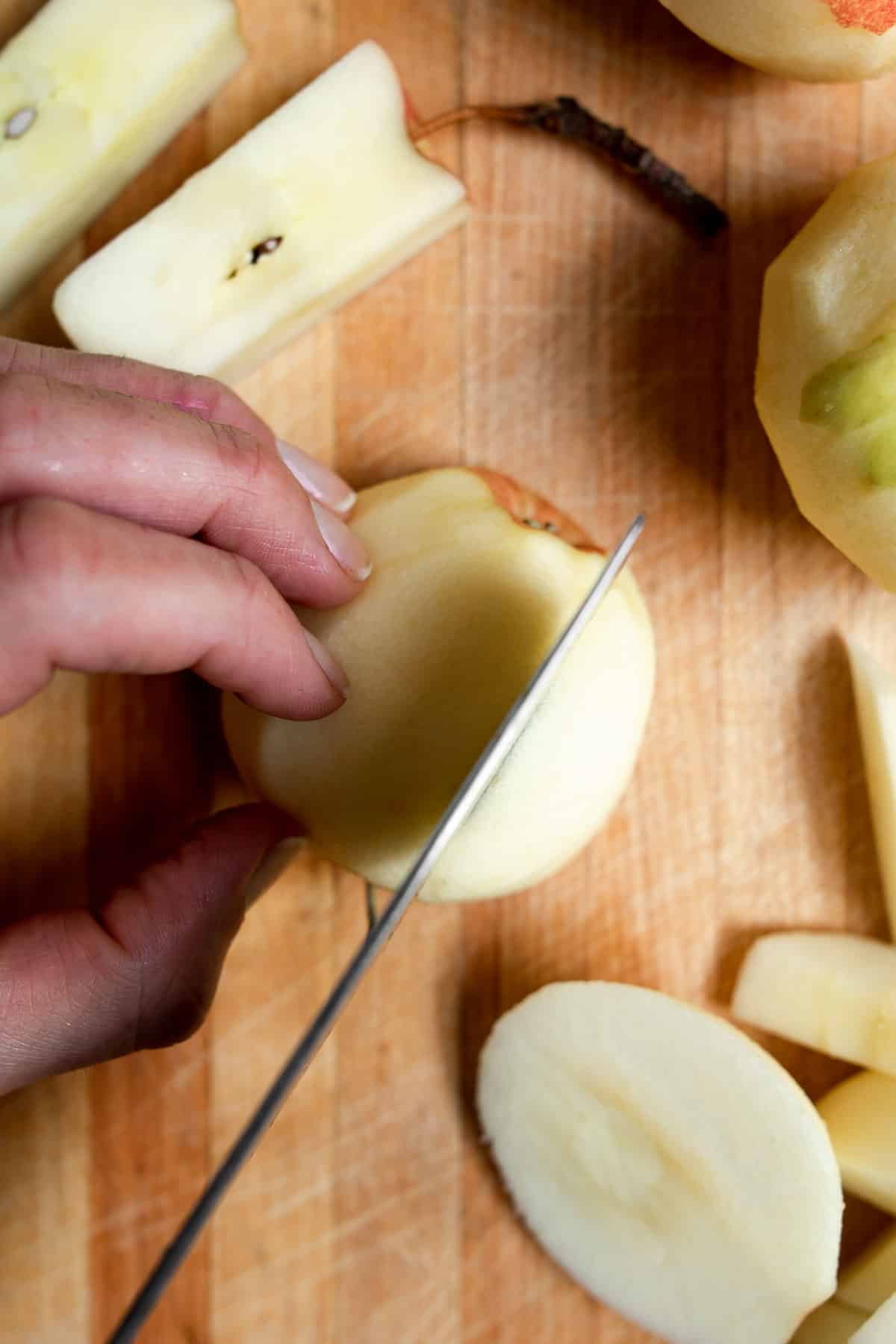 knife coring and cutting apples on wooden cutting board.