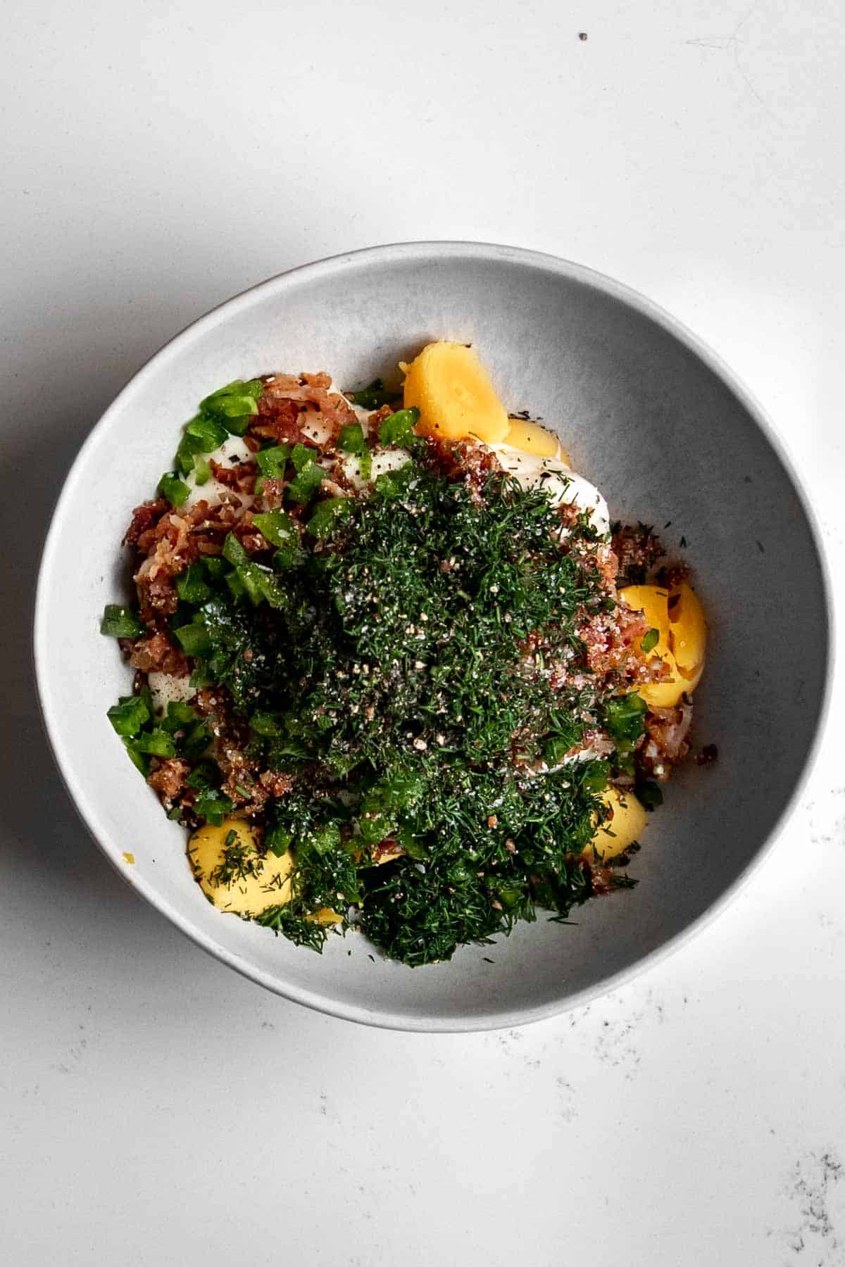 egg yolks, bacon, jalapeno, dill and back pepper in a bowl.