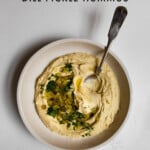 hummus in a bowl topped with chopped dill pickles and dill with text graphic.
