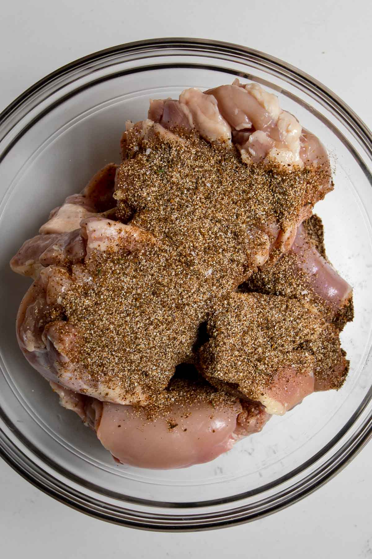 chicken thighs covered in dry brine spices in a bowl.
