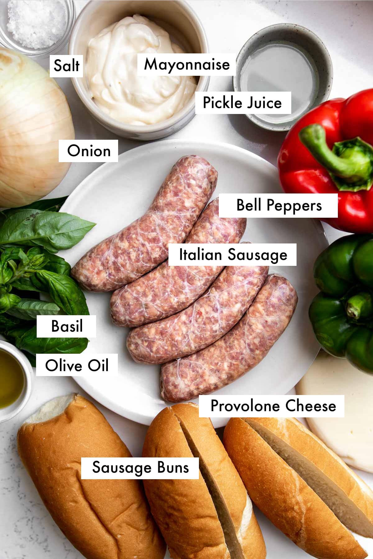 Small plate with 4 sausages, surrounded by 3 sausage buns, olive oil, fresh basil, garlic, onion, sea salt flakes, mayonnaise, pickle juice, red pepper, green pepper, and provolone cheese.