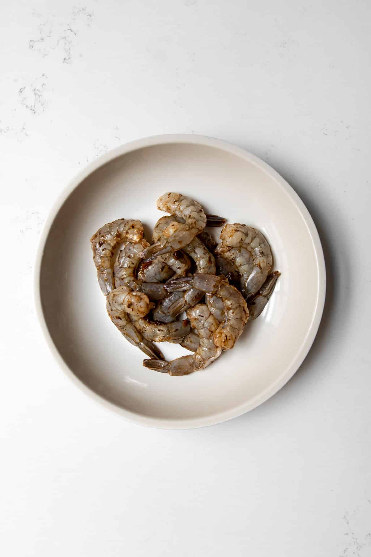 raw shrimp marinating with jerk in a bowl.